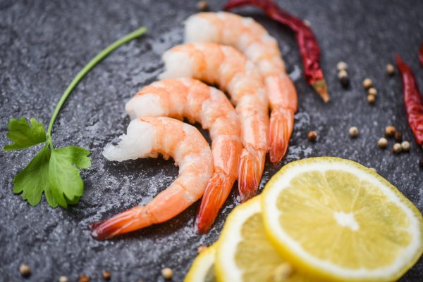 fresh shrimps served on the dark plate / boiled peeled shrimp prawns cooked with spices lemon in the seafood restaurant